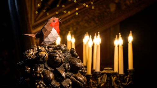 A handmade paper robin decoration against the backdrop of a glowing chandelier